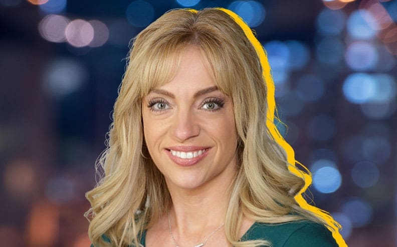 A smiling woman with long blonde hair is wearing a green top. The background is blurred with blue and orange lights, and there is a yellow outline around her silhouette.
