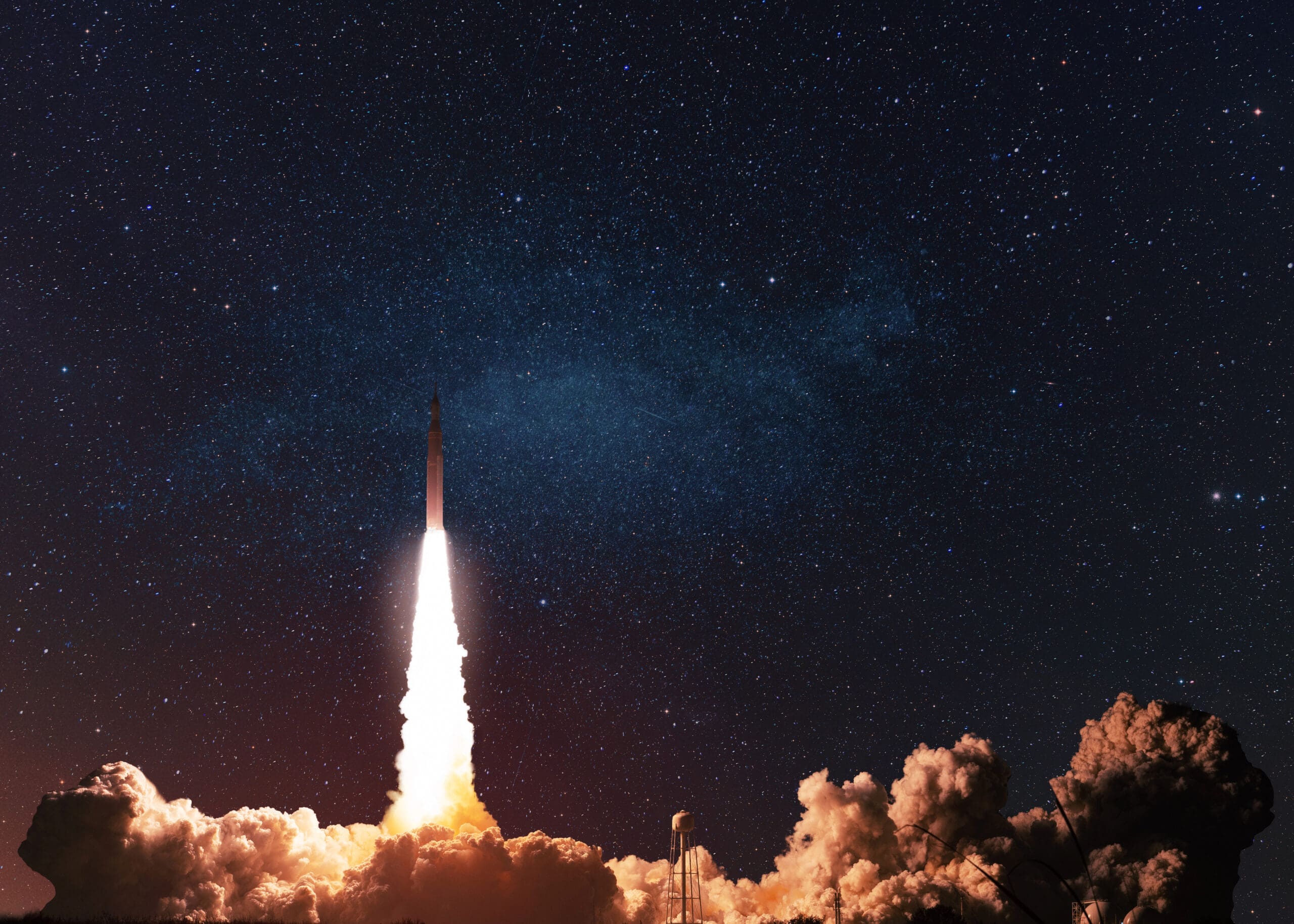 A rocket launches into the night sky, leaving a bright trail of fire and smoke, with countless stars visible in the background.